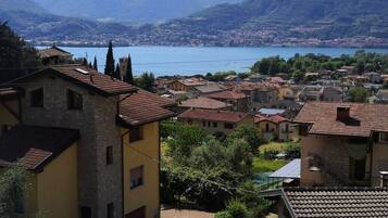 A residential area with stone buildings and a view of a lake and mountains.
