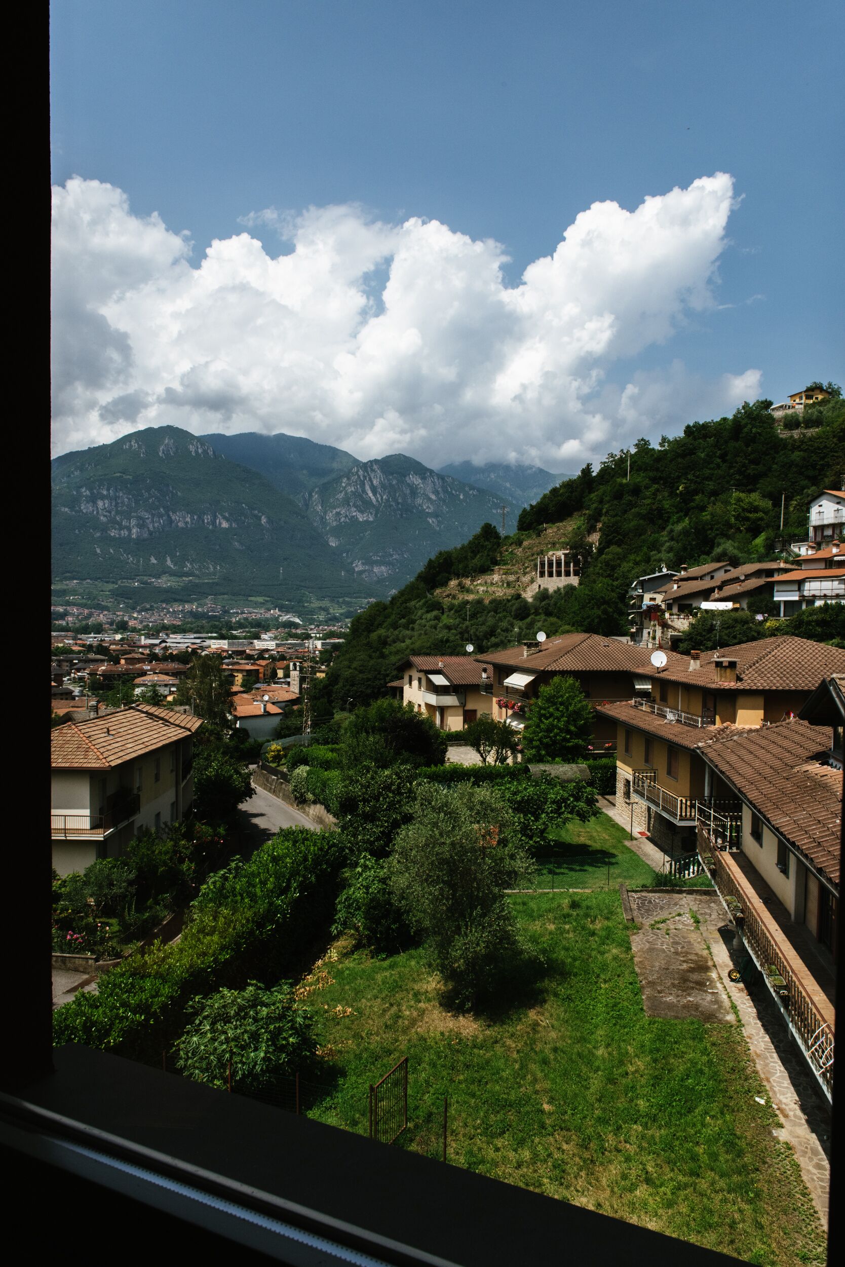 A residential area with houses, a small courtyard, and mountains in the background.