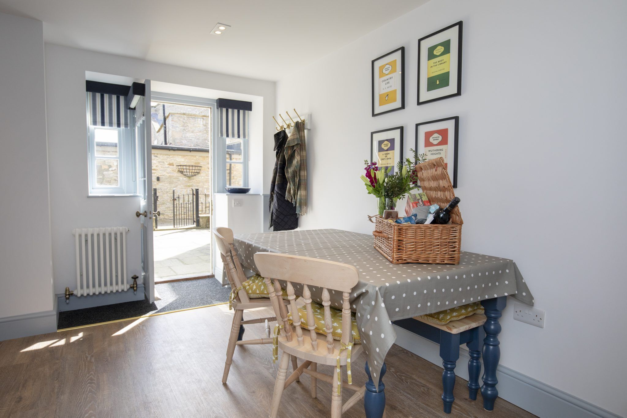 A dining area with a table set for two, a chair, a radiator, and a window with curtains.