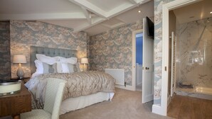 A bedroom with a large bed, two bedside lamps, a wooden nightstand, and a chair. - The Carriage House - sleeps 4 guests  in 2 bedrooms (Leyburn)