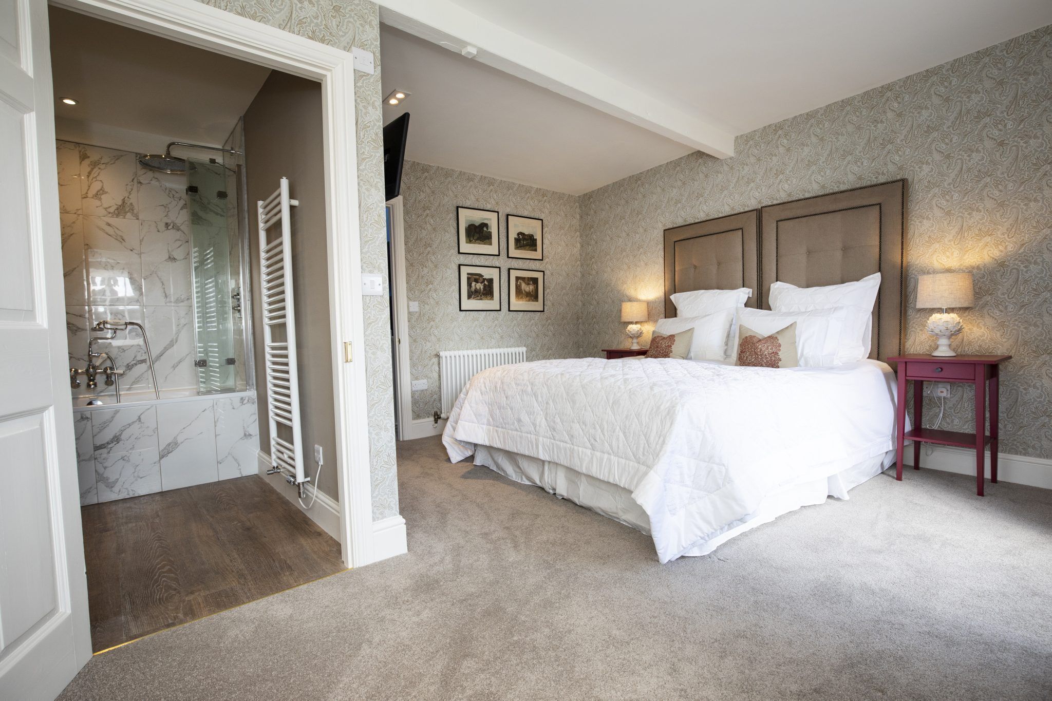 A bedroom with a large bed, a bedside table with a lamp, a radiator, and a shower area with a glass door.