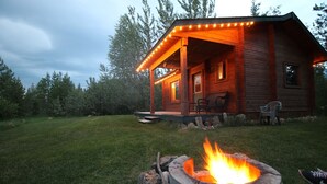 Une cabane en bois avec un porche, un foyer et des sièges d’extérieur.
