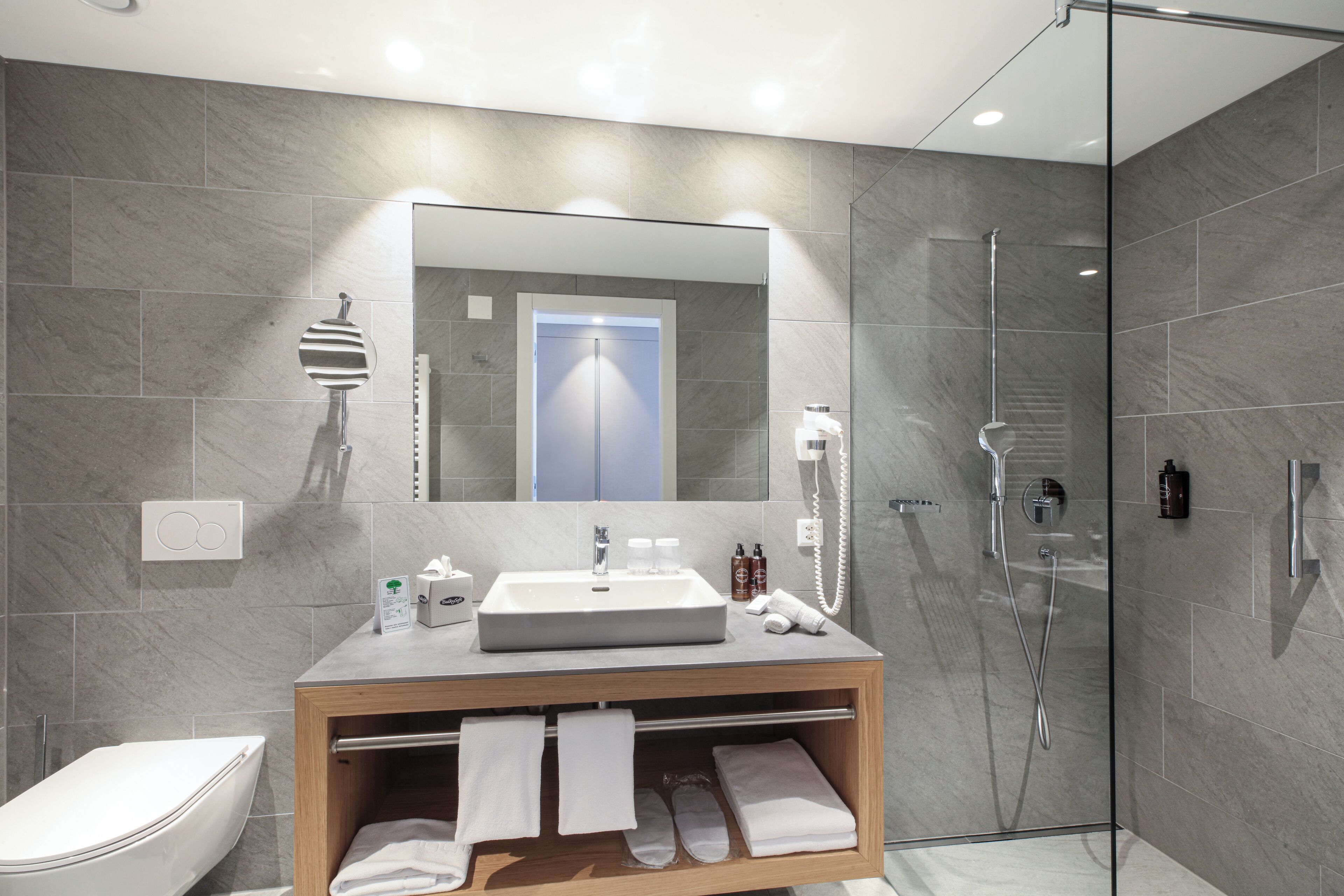 Un bagno moderno con un grande specchio, un lavabo e una cabina doccia in vetro.