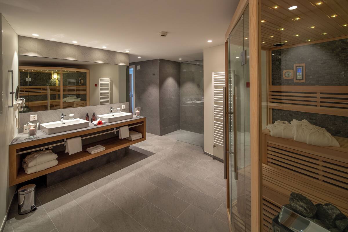 A modern bathroom with two sinks, a large mirror, and a shower area.