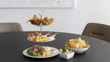 Un soporte de tres niveles para postres con diversos pasteles y un bol de galletas sobre una mesa redonda.