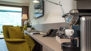 A modern hotel room with a coffee machine, a desk, a telephone, and a chair.