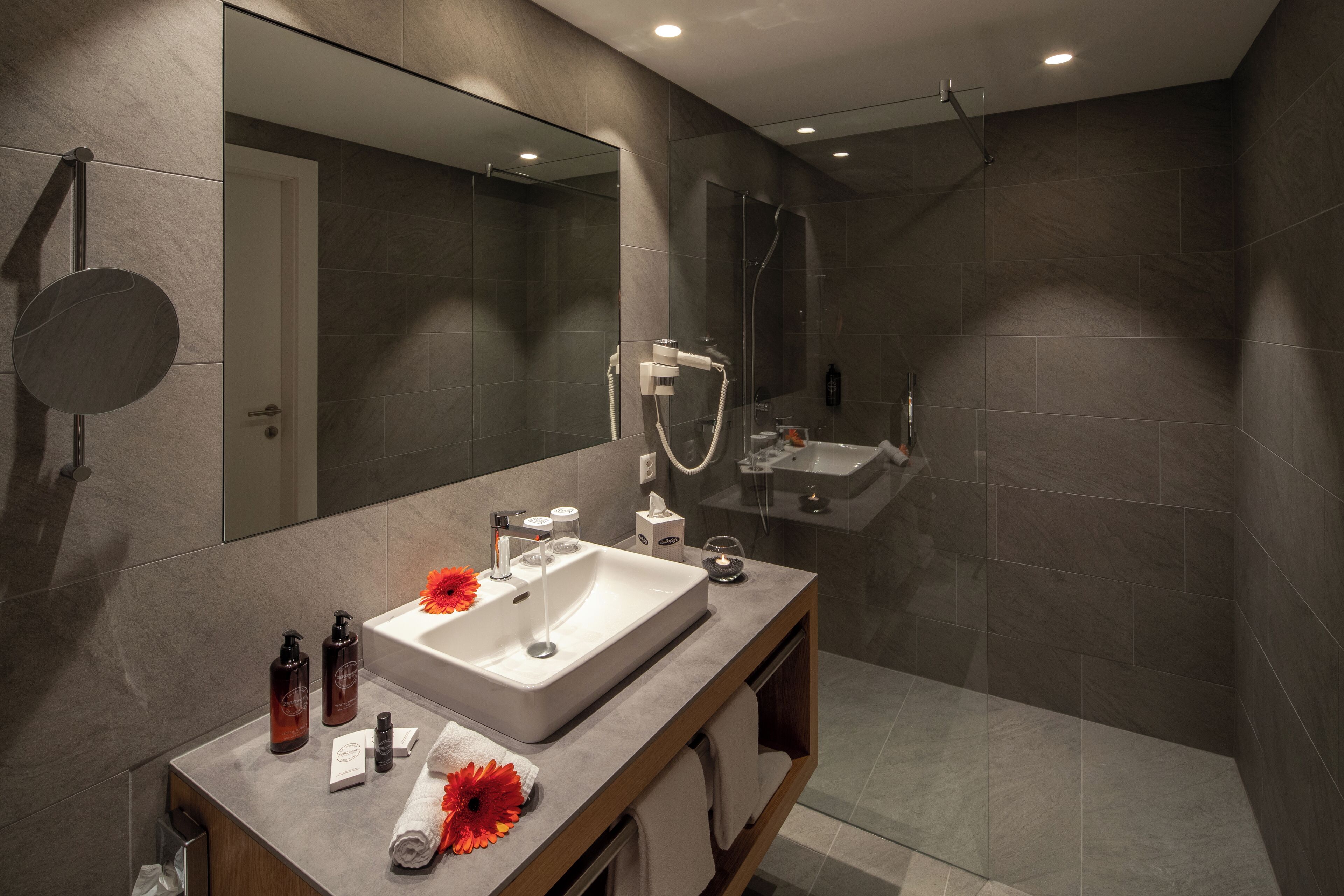 A modern bathroom with a large mirror, a sink, and a shower area.