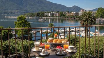 Una mesa con alimentos para el desayuno y vistas a un puerto deportivo y montañas.