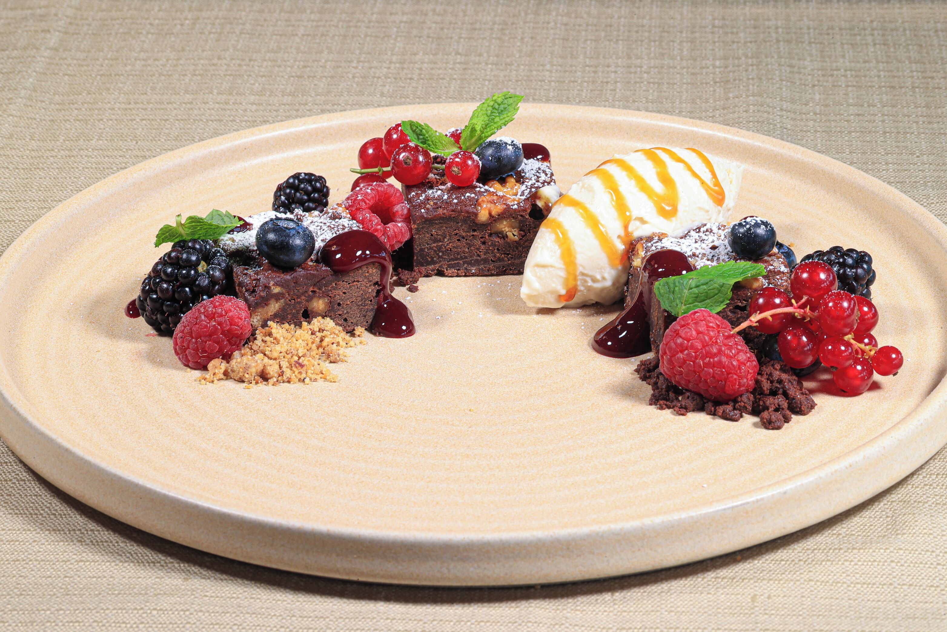 Un plato de postre con diversas frutas y un hilo de salsa.
