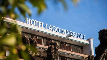 Hotel con un letrero que dice "HOTEL LAGO MAGGIORE" contra un cielo azul despejado.