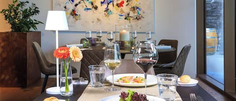 A dining table set with plates of food, glasses of wine, and a vase of flowers.