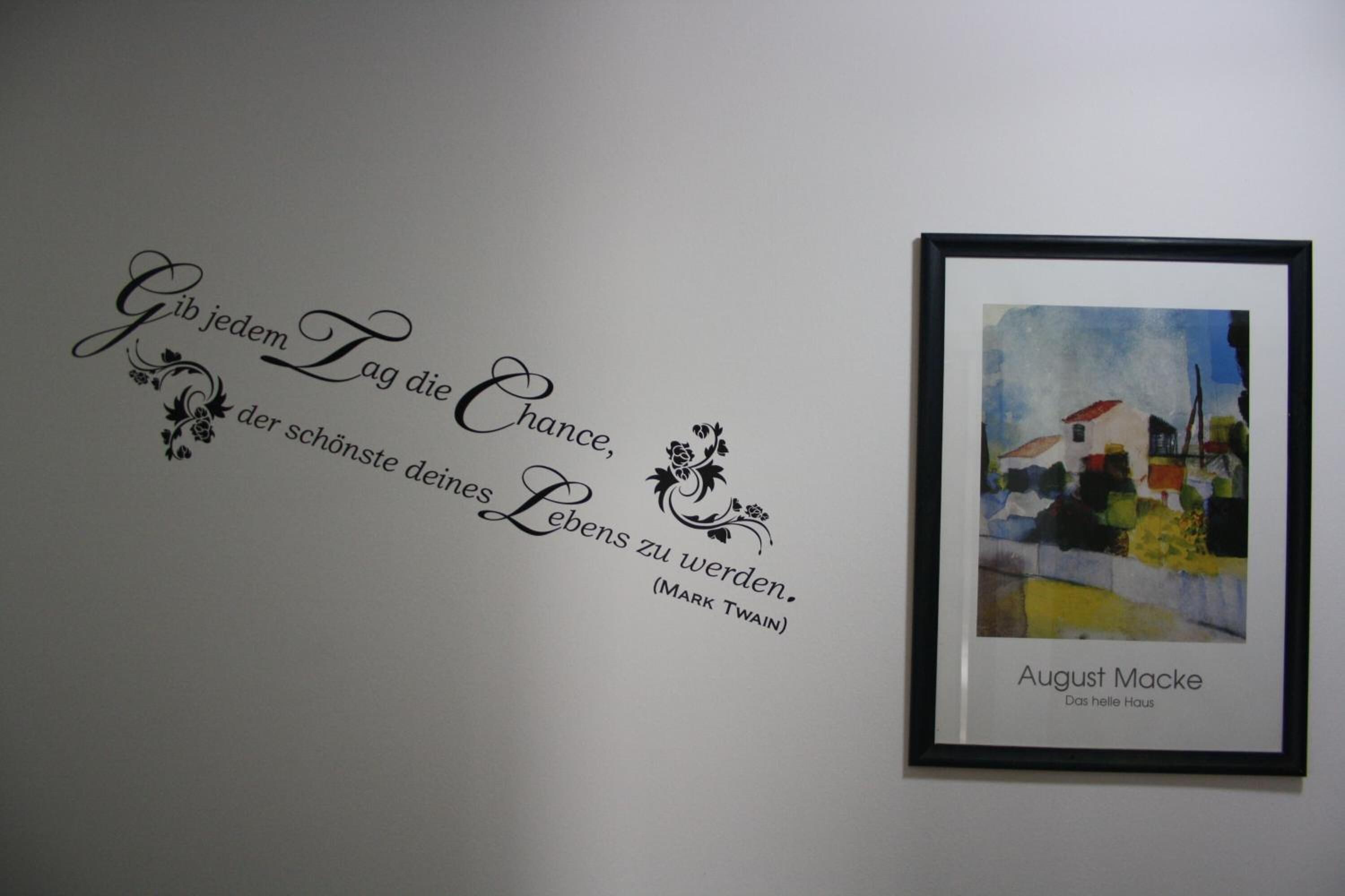 Eine Wand mit einem deutschen Zitat und einem Gemälde von August Macke in einem Rahmen.