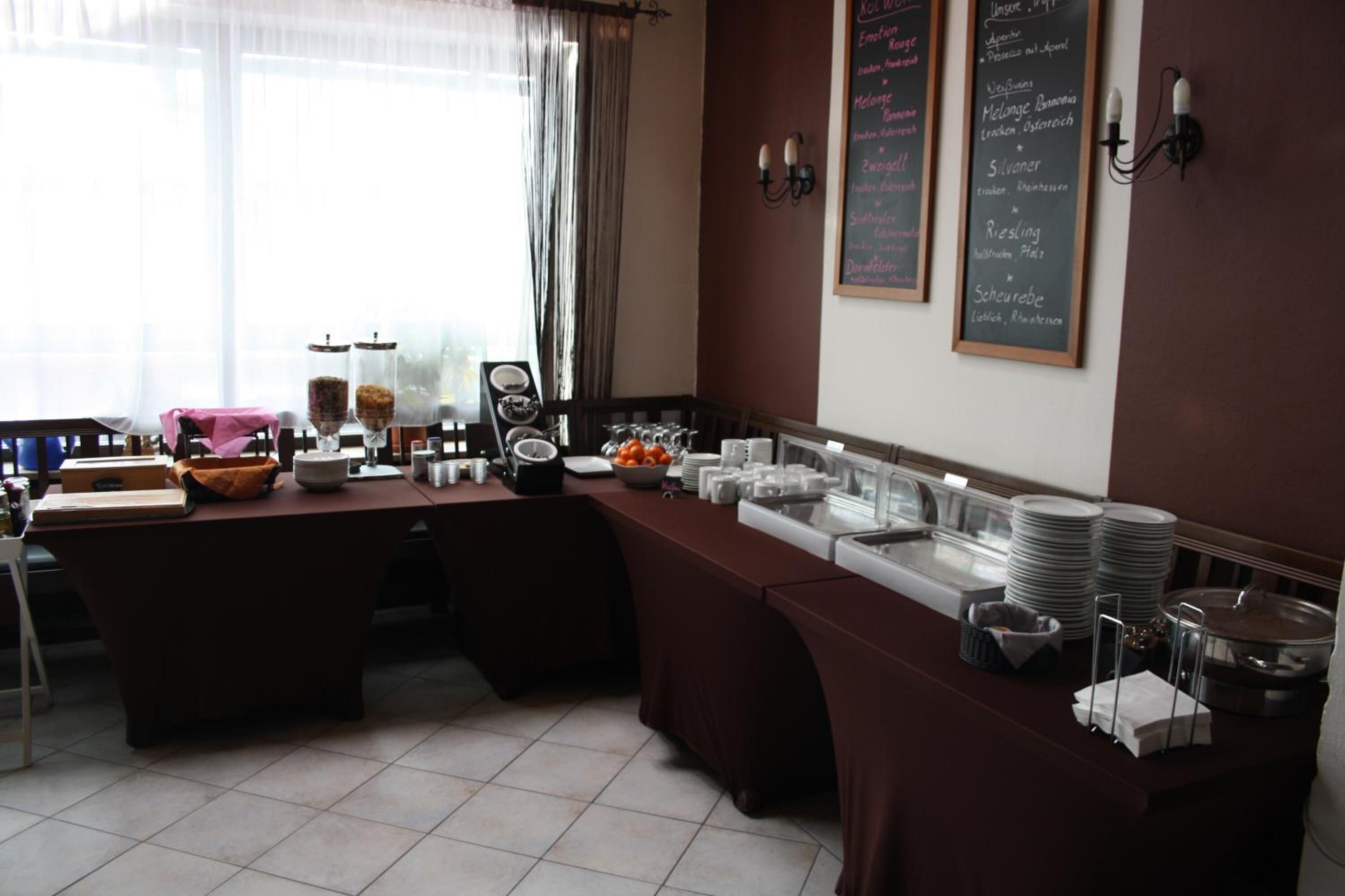 Montaje de un bufé de desayuno con diversas opciones de comida y un menú en una pizarra.