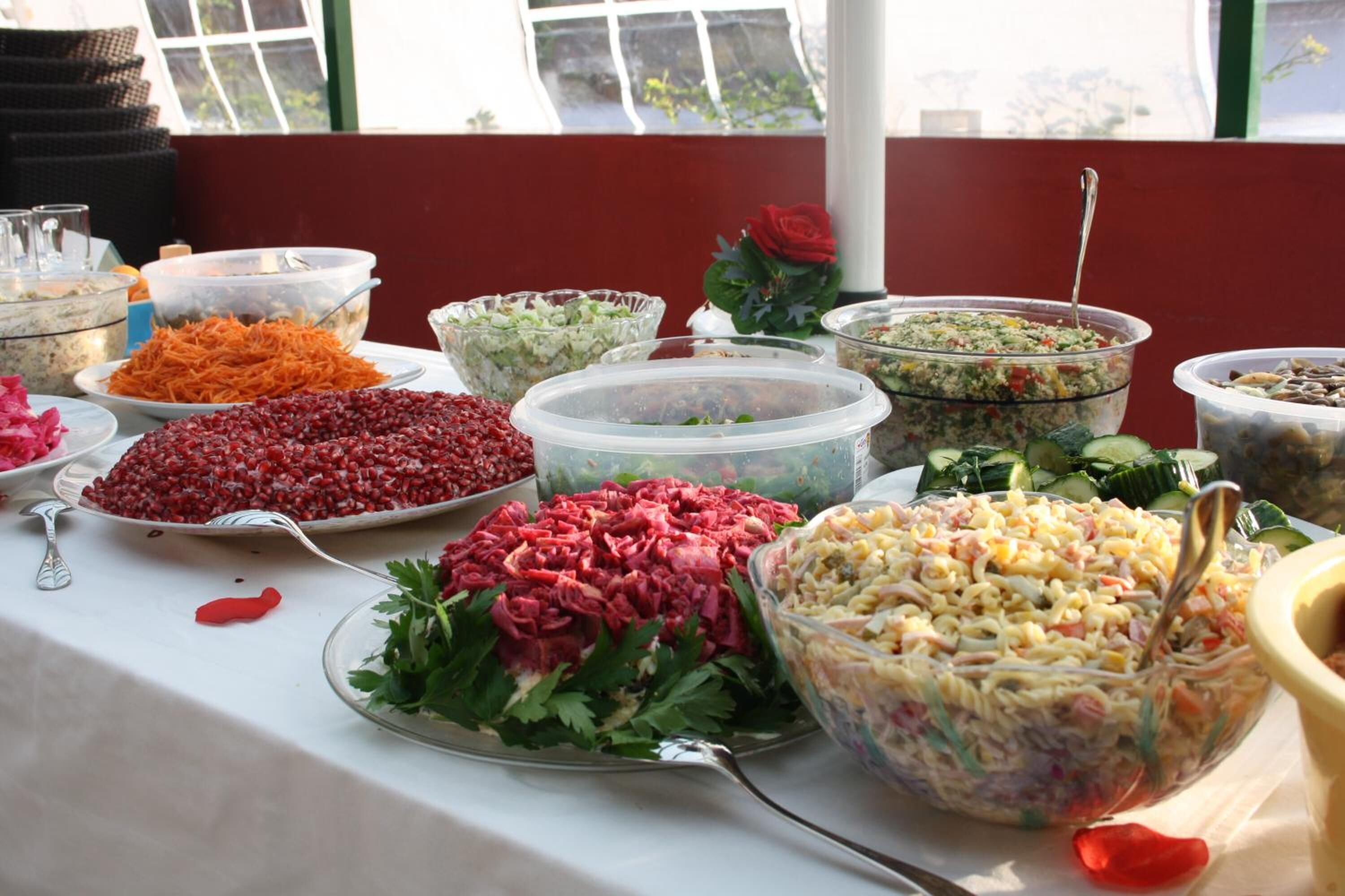 A buffet table with various dishes including salads, shredded vegetables, and pasta salad.