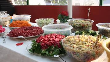 A buffet table with various dishes including salads, shredded vegetables, and pasta salad.