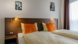 A hotel room with two beds, a wooden headboard, and two wall-mounted light fixtures. - Gasthof-Pension Kirchenwirt (Niederaichbach)
