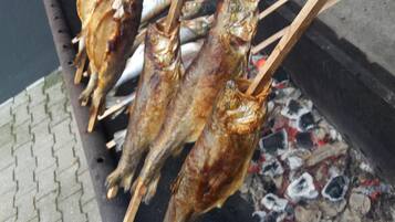 Mehrere gegrillte Hähnchen am Spieß über offenem Feuer.