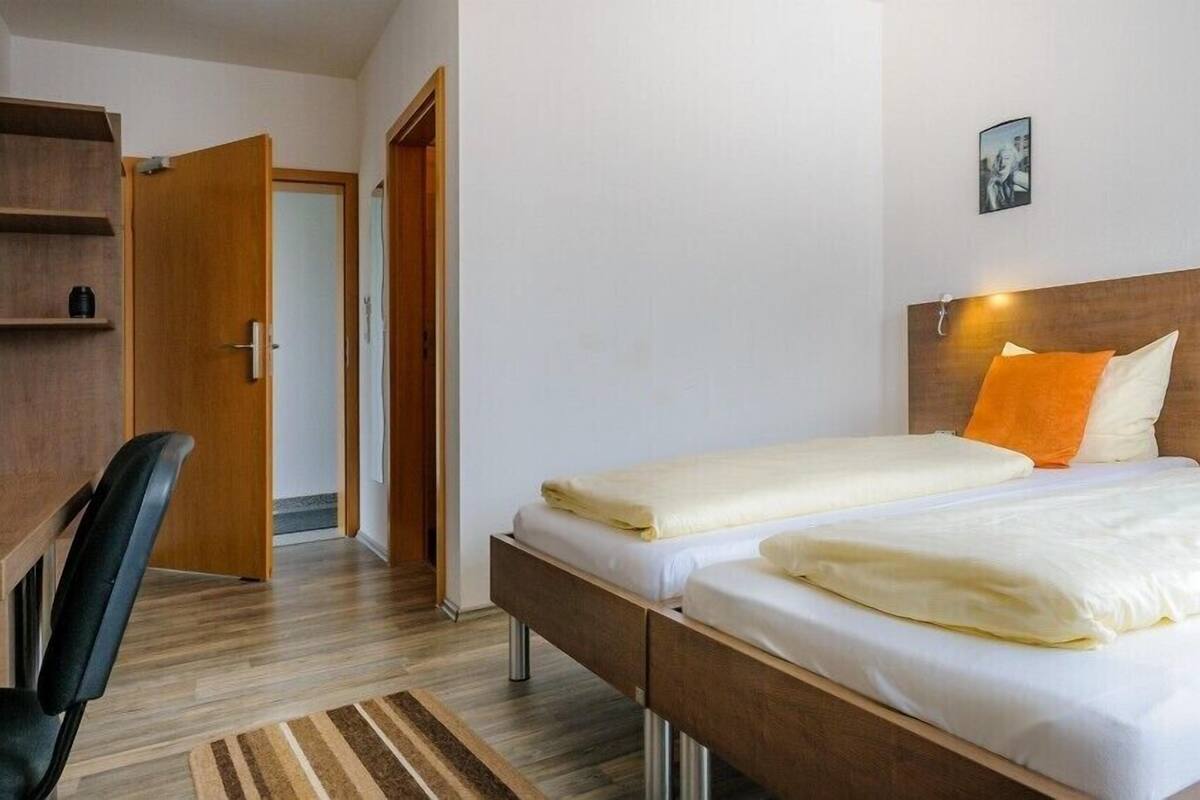 A hotel room with two beds, a desk, and a chair.