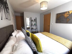 A hotel room with a bed, a wardrobe, a mirror, a shelf with towels, and a world map on the wall. - George Hudson Ground floor apartment with parking (York)