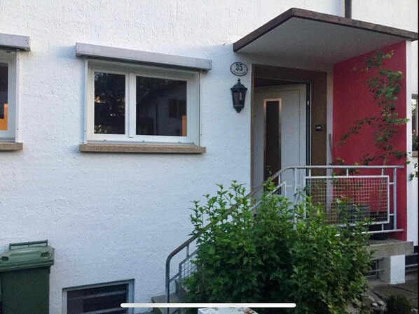A building with white walls, a red door, and a small balcony with a metal railing. - House at Rotsee Lake Lucerne (Lucerne)