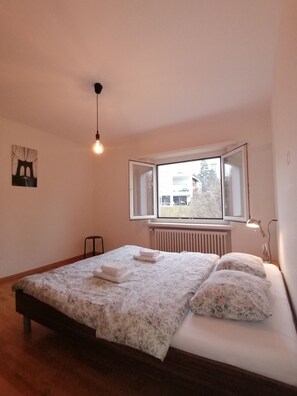 A bedroom with a bed, a radiator, a window, and a hanging light fixture. - House at Rotsee Lake Lucerne (Lucerne)