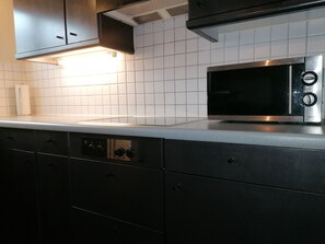 A kitchen with a microwave, stainless steel cabinets, and a tiled backsplash.