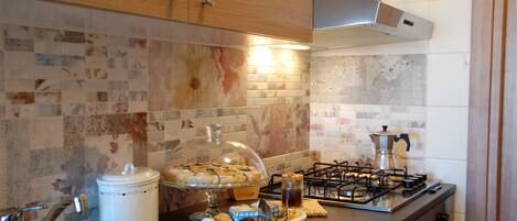 A kitchen with wooden cabinets, a tiled backsplash, a stove, and a sink.