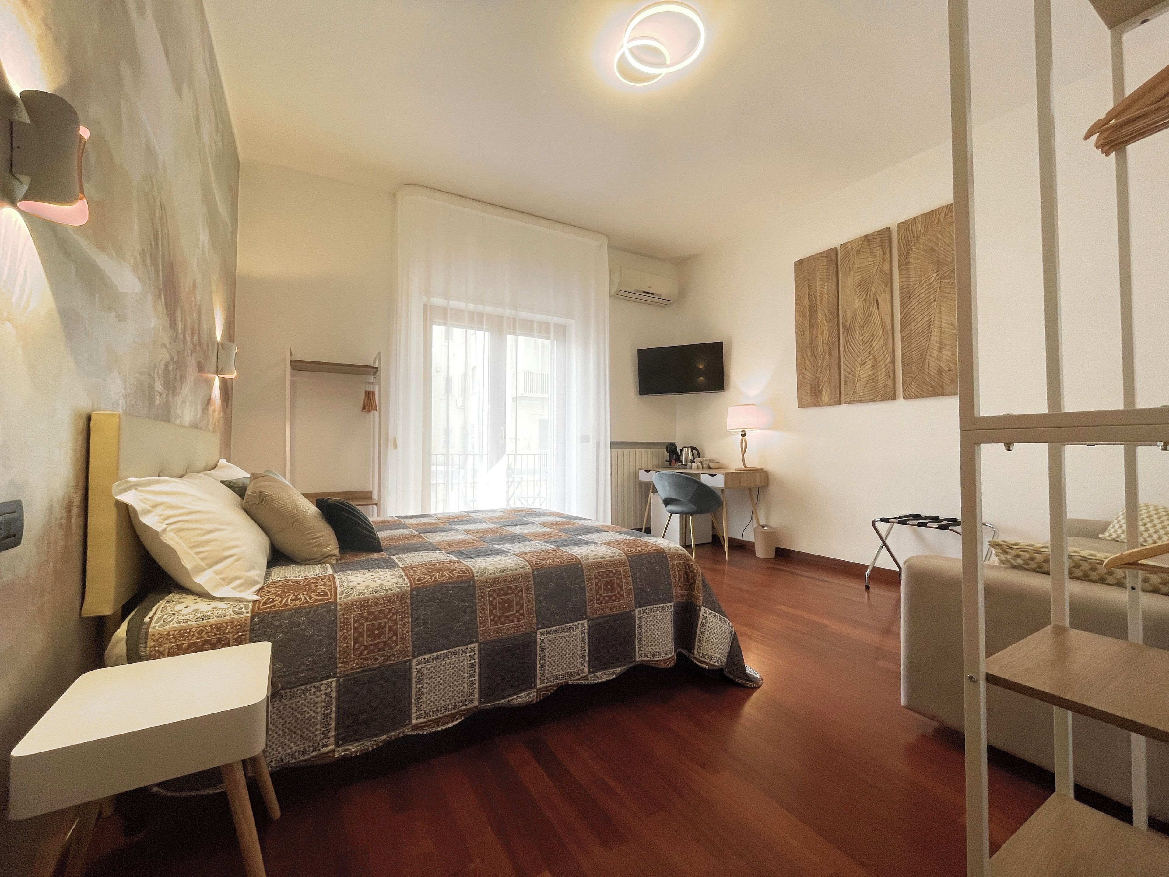 Een hotelkamer met een bed, een bureau, een stoel, een televisie en kunstwerken aan de muren.