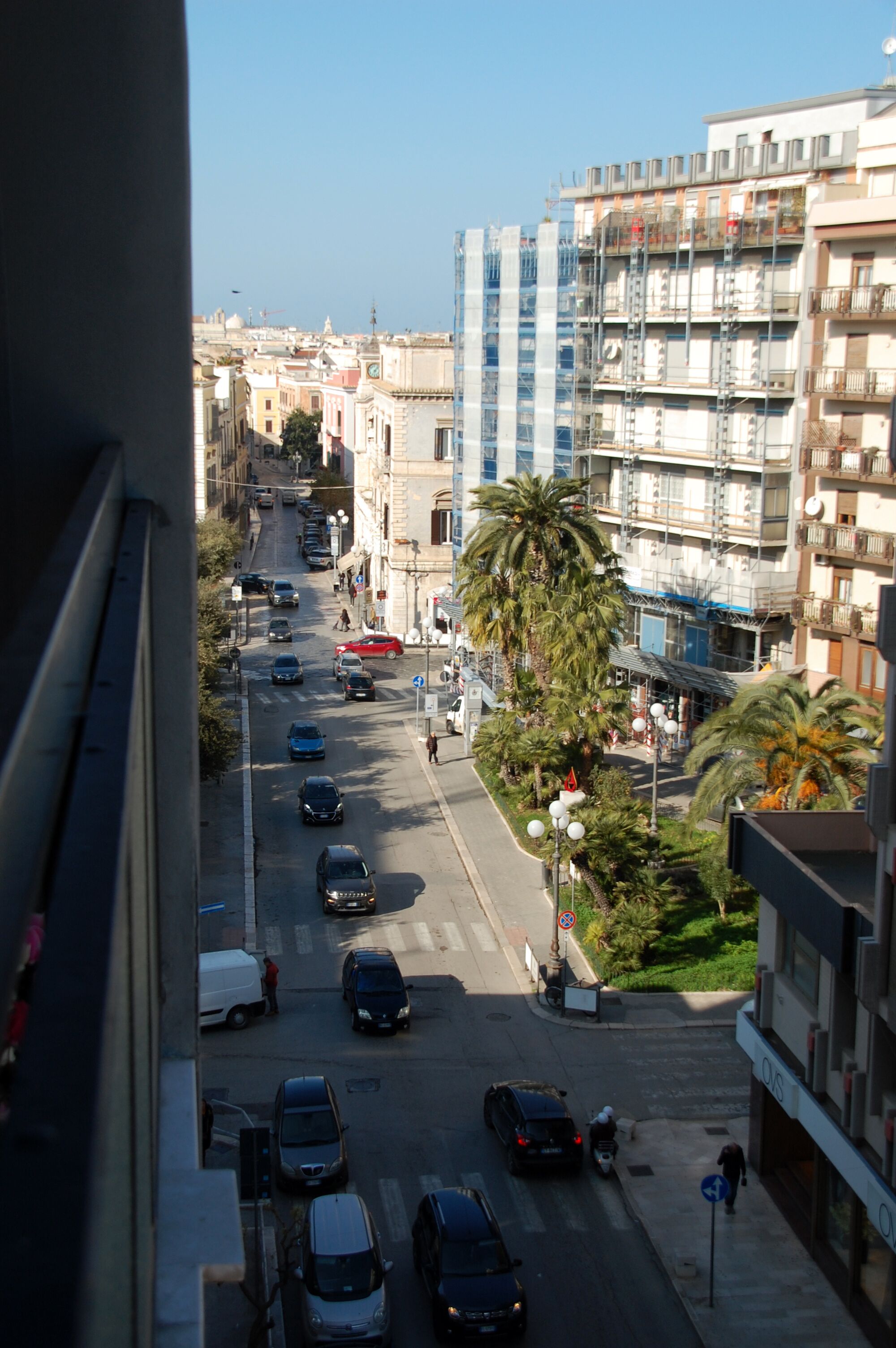 A city street with cars, a pedestrian, and buildings.