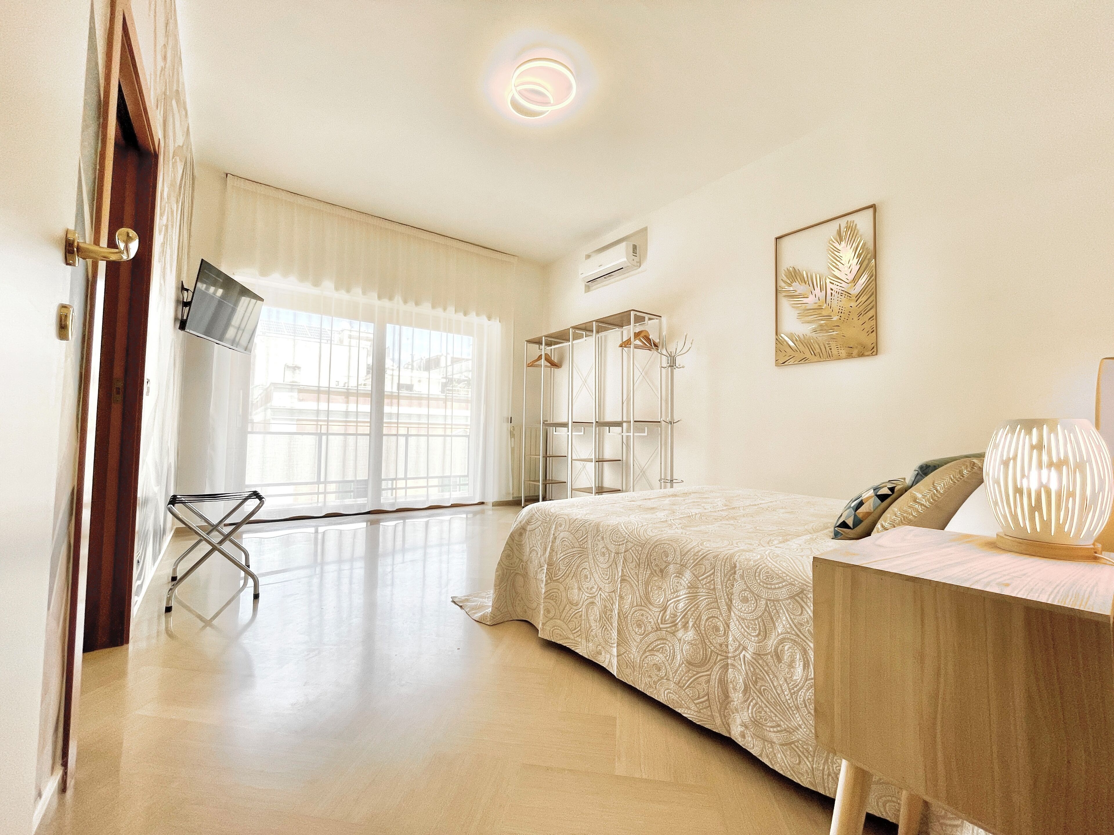 A bedroom with a bed, a TV, a wardrobe, and a window with curtains.