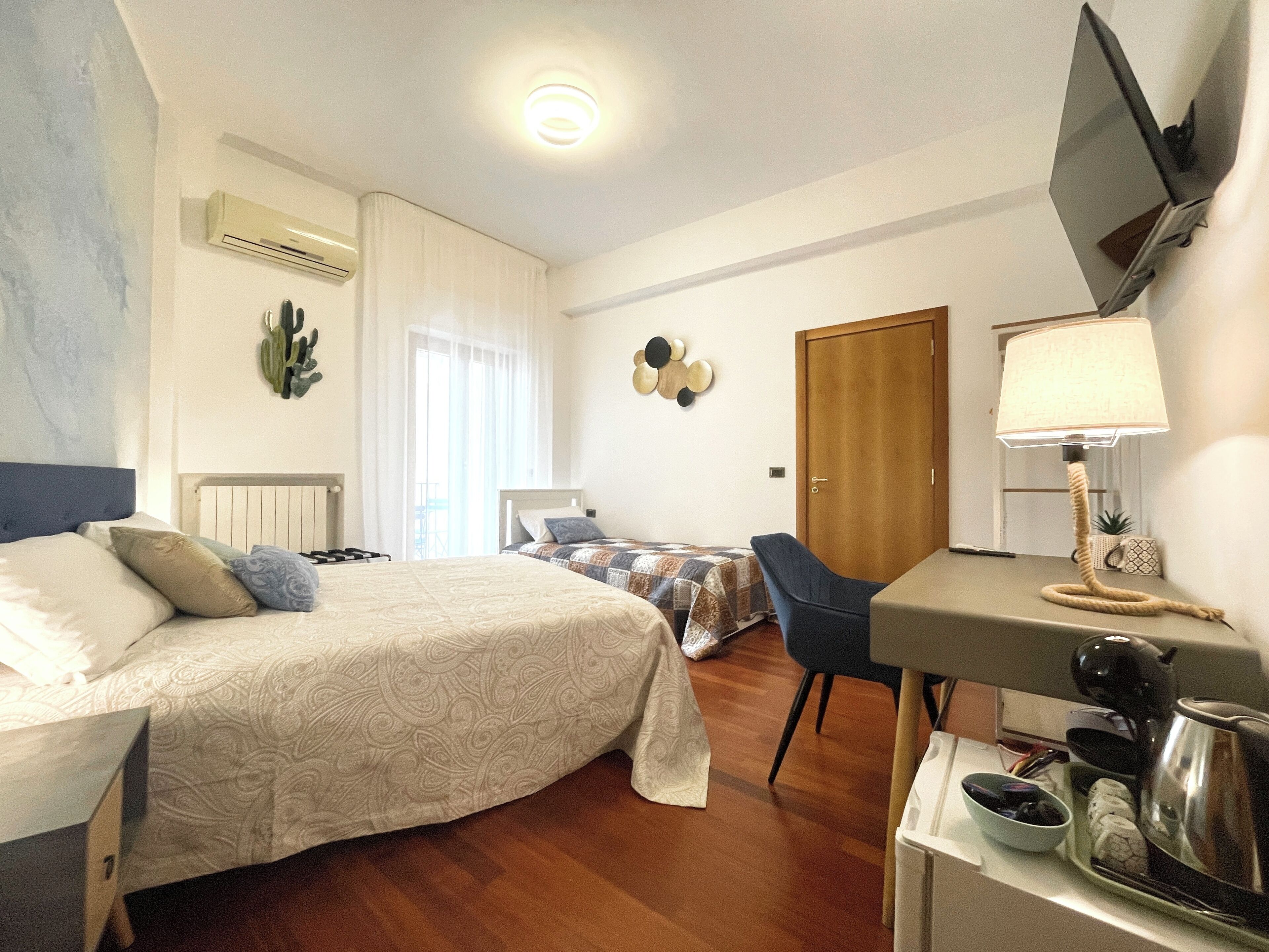 Habitació d'hotel amb llit, escriptori, cadira, televisió i porta.