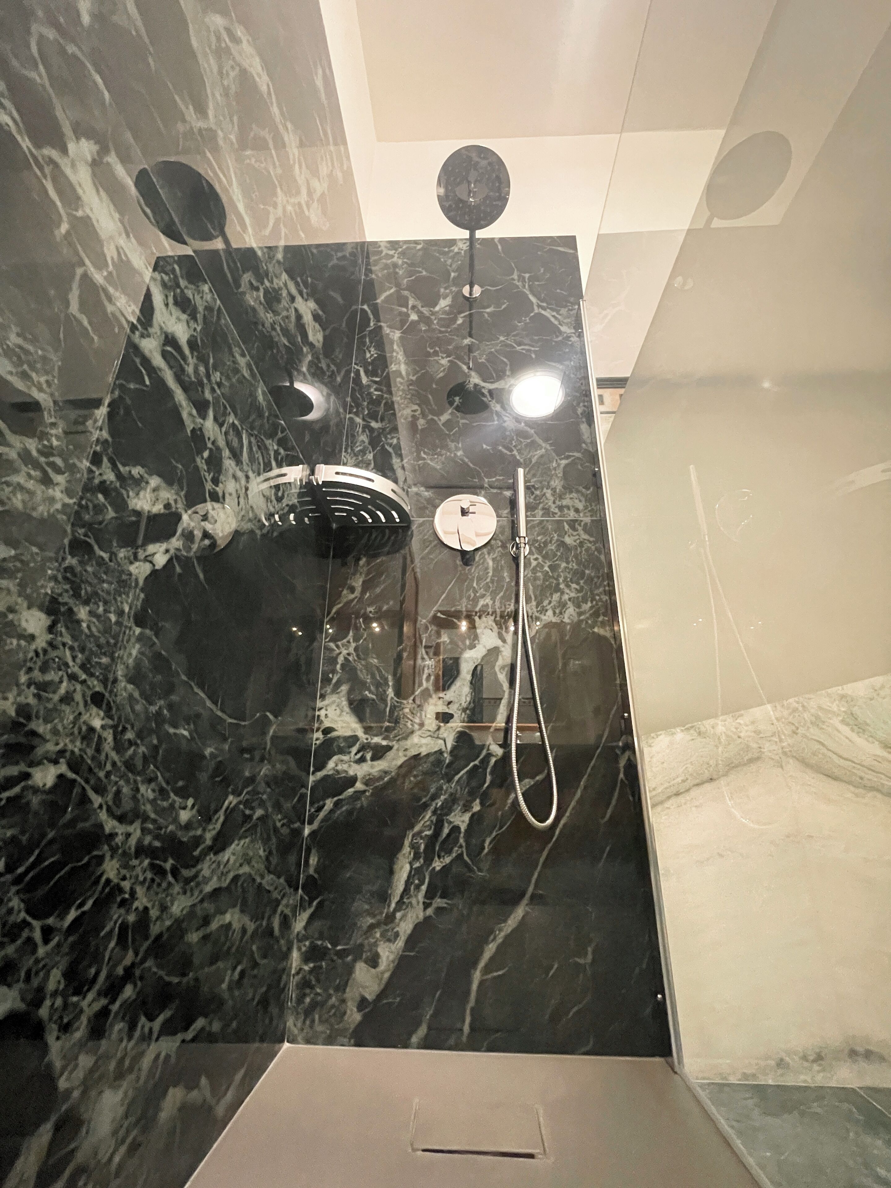 A bathroom with a black marble wall, a shower area, and a toilet.