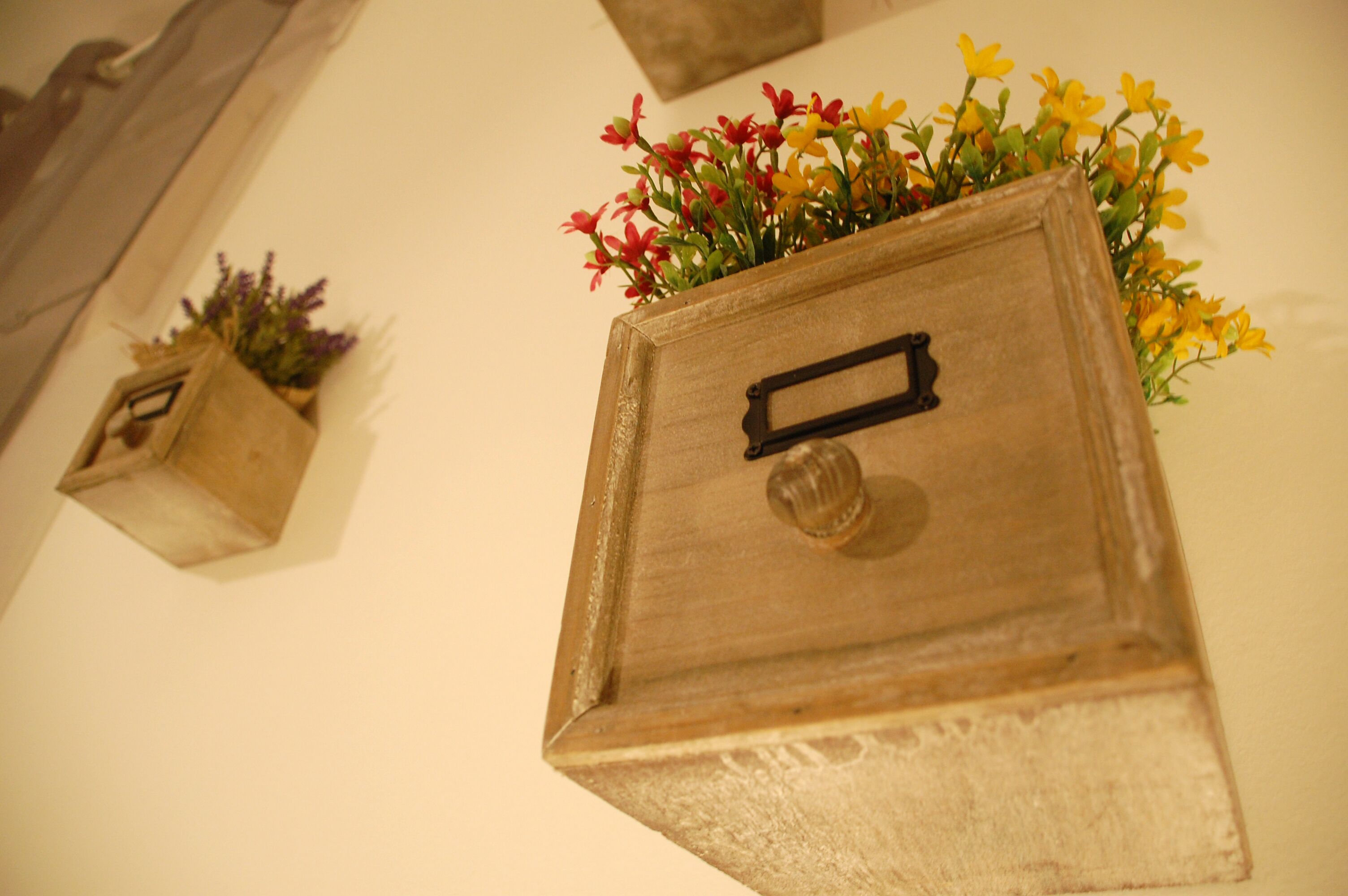 Una caja de madera con asa y un pequeño orificio para llave, que contiene un ramo de flores.