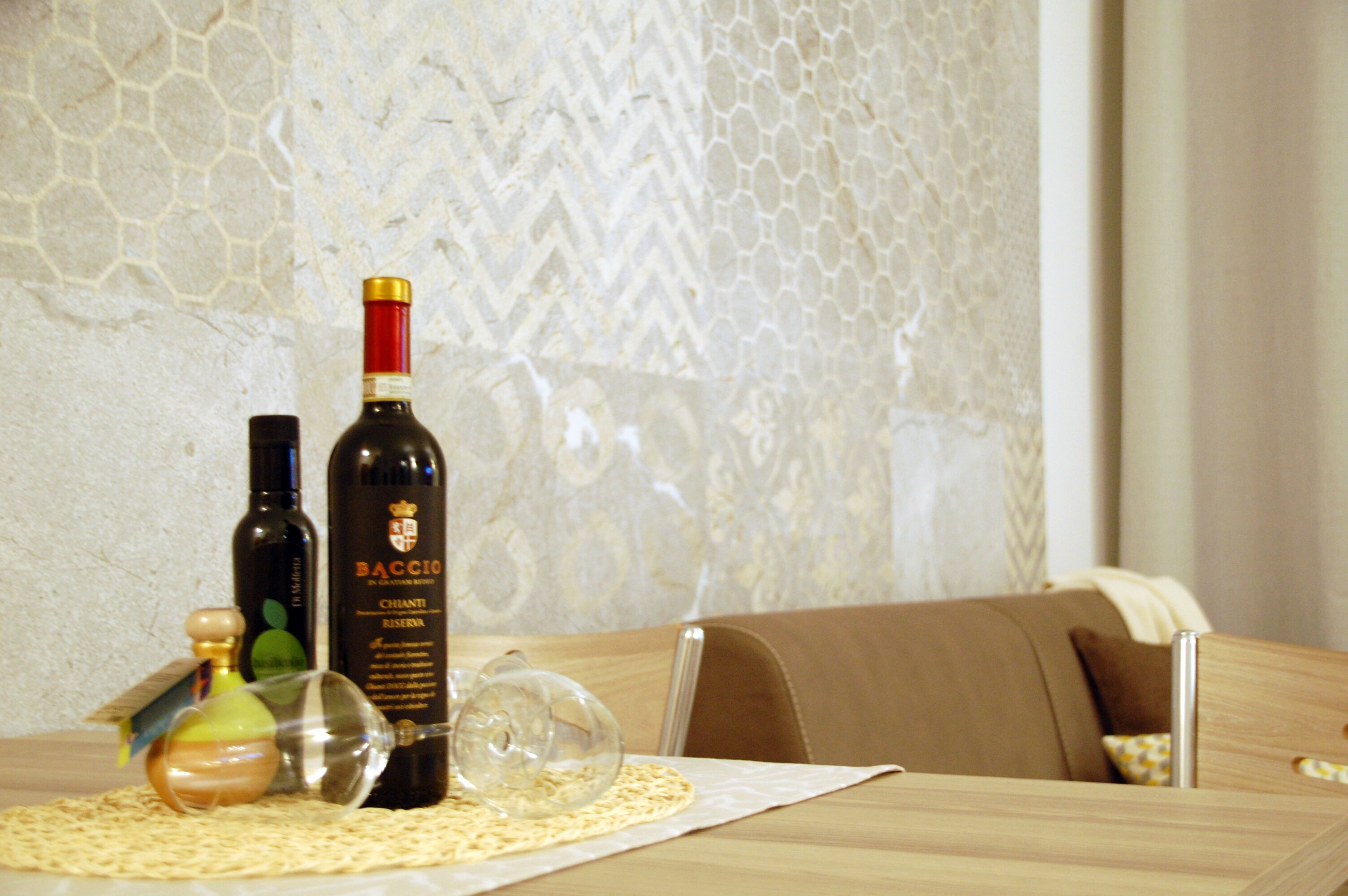 Un tavolo con due bottiglie di vino Baccio Chianti Riserva, un decanter e un bicchiere su un sottobicchiere.