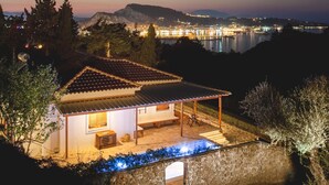 Una casa con piscina, patio y vista a un paisaje urbano al atardecer.