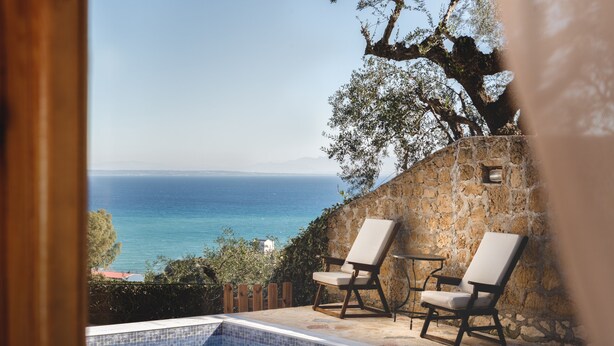 Vista de una piscina con dos tumbonas mirando al mar.
