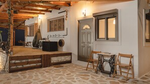 Una habitación rústica con suelo de piedra, vigas de madera, una máquina de coser y un banco.