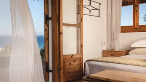 Un dormitorio con cama de madera, mesita de noche y vistas al océano.