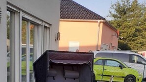 A patio with a wicker chair, a small table, and a concrete planter. - Quality vacation rental in Berlin-Kaulsdorf (Bezirk Marzahn-Hellersdorf)
