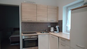 A compact kitchen with a stove, oven, sink, and a coffee maker. - Quality vacation rental in Berlin-Kaulsdorf (Bezirk Marzahn-Hellersdorf)