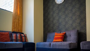 Una habitación con un conjunto de sofás, un papel tapiz decorado y un reloj.