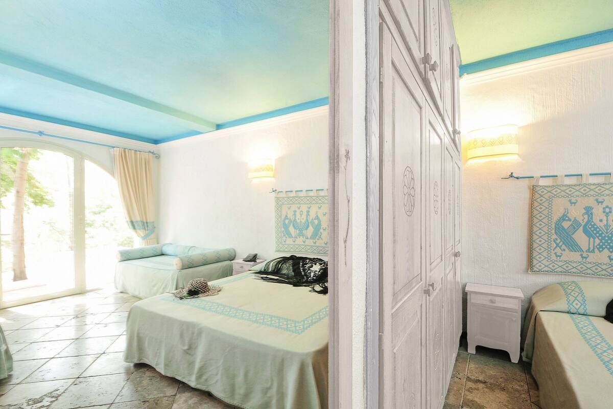 A bedroom with a bed, a nightstand, a dresser, and a window with curtains.