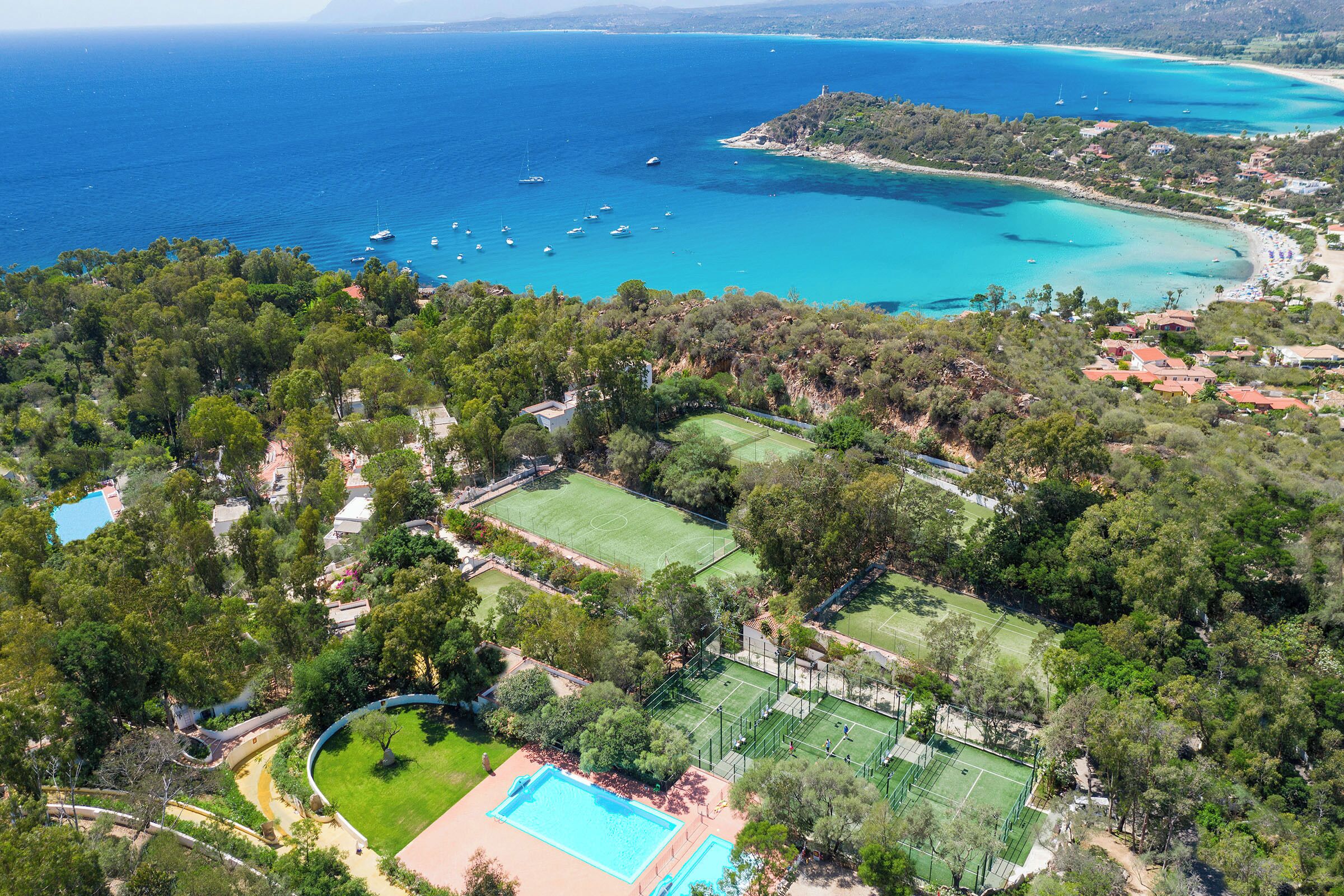 Vista aerea di una proprietà costiera con piscina, campi da tennis e spiaggia.