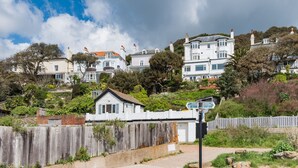 A hillside residential area with houses, a wooden fence, and a sign indicating a coastal tour. - Pebbles by Bloom Stays - sleeps 2 with the most amazing sea views! (Folkestone)