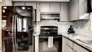 Une cuisine moderne dotée d’appareils électroménagers en acier inoxydable, d’un plan de travail en marbre et d’un dosseret carrelé.