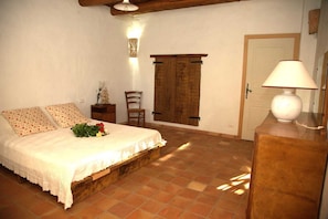 Ein Schlafzimmer mit einem Bett, einem Nachttisch, einem Sessel, einer Holztür und einer Lampe.