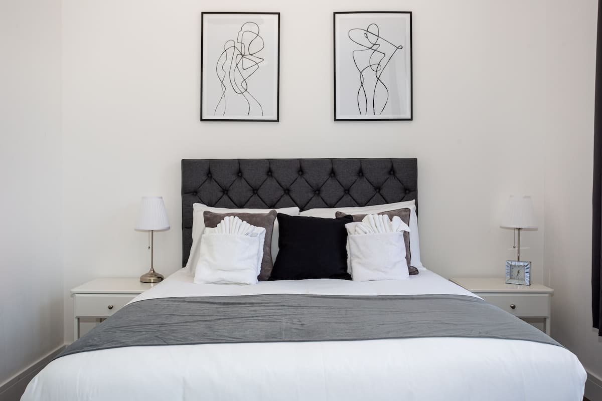 A neatly arranged bedroom with a large bed, two bedside tables, and two framed artworks on the wall.
