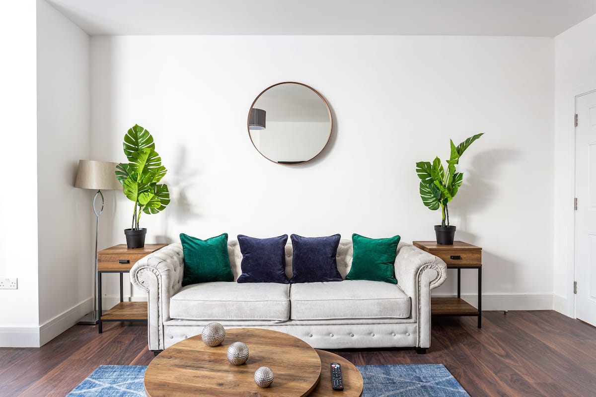A living room with a sofa, two side tables, a coffee table, and two potted plants.