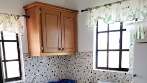 Een keuken met houten kastjes, een betegelde achterwand, een spoelbak, een fornuis en een koelkast.