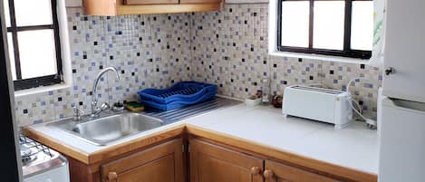A kitchen with wooden cabinets, a tiled backsplash, a sink, a stove, and a refrigerator.